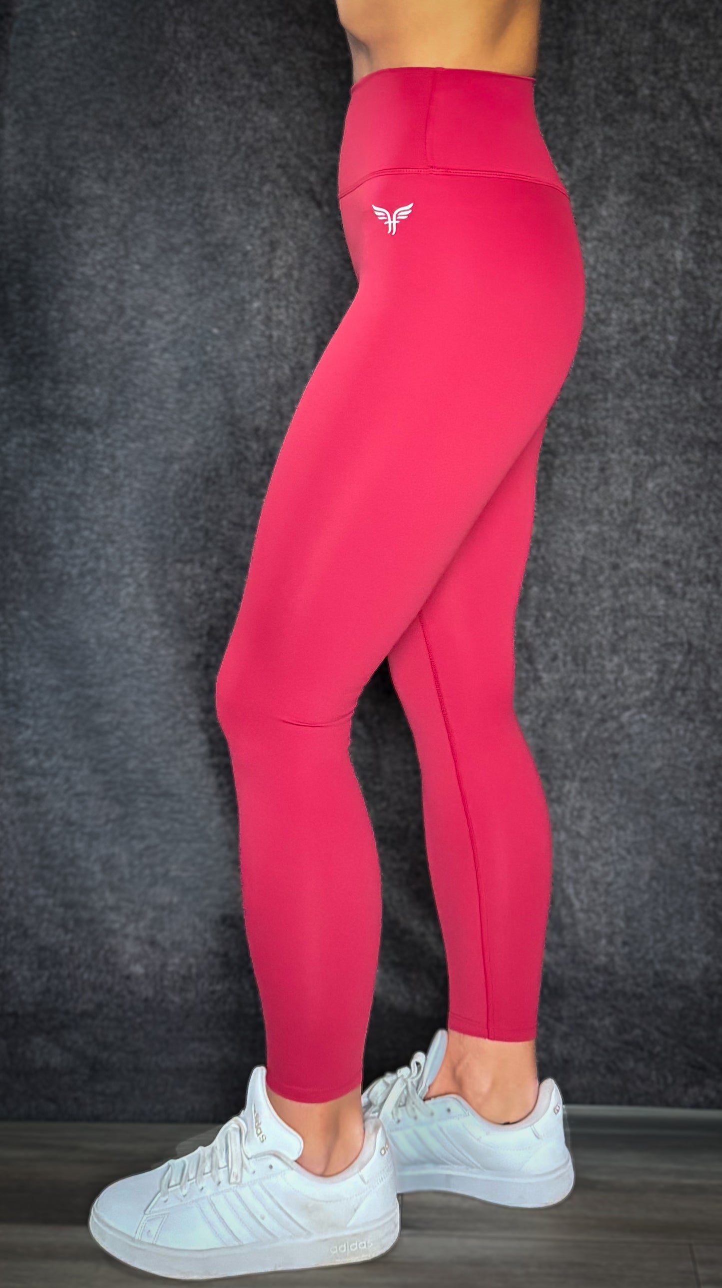 Person wearing bright pink leggings with a logo on a dark background